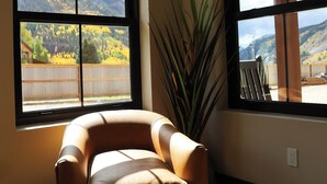 Ein Zimmer mit großem Fenster, einem Sessel und einer Pflanze.