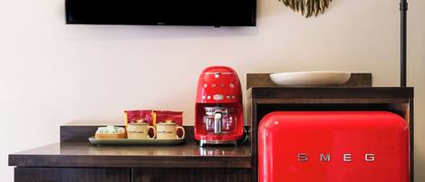 A modern living room with a dark wooden cabinet, a red vintage-style refrigerator, a coffee maker, and a mounted television.