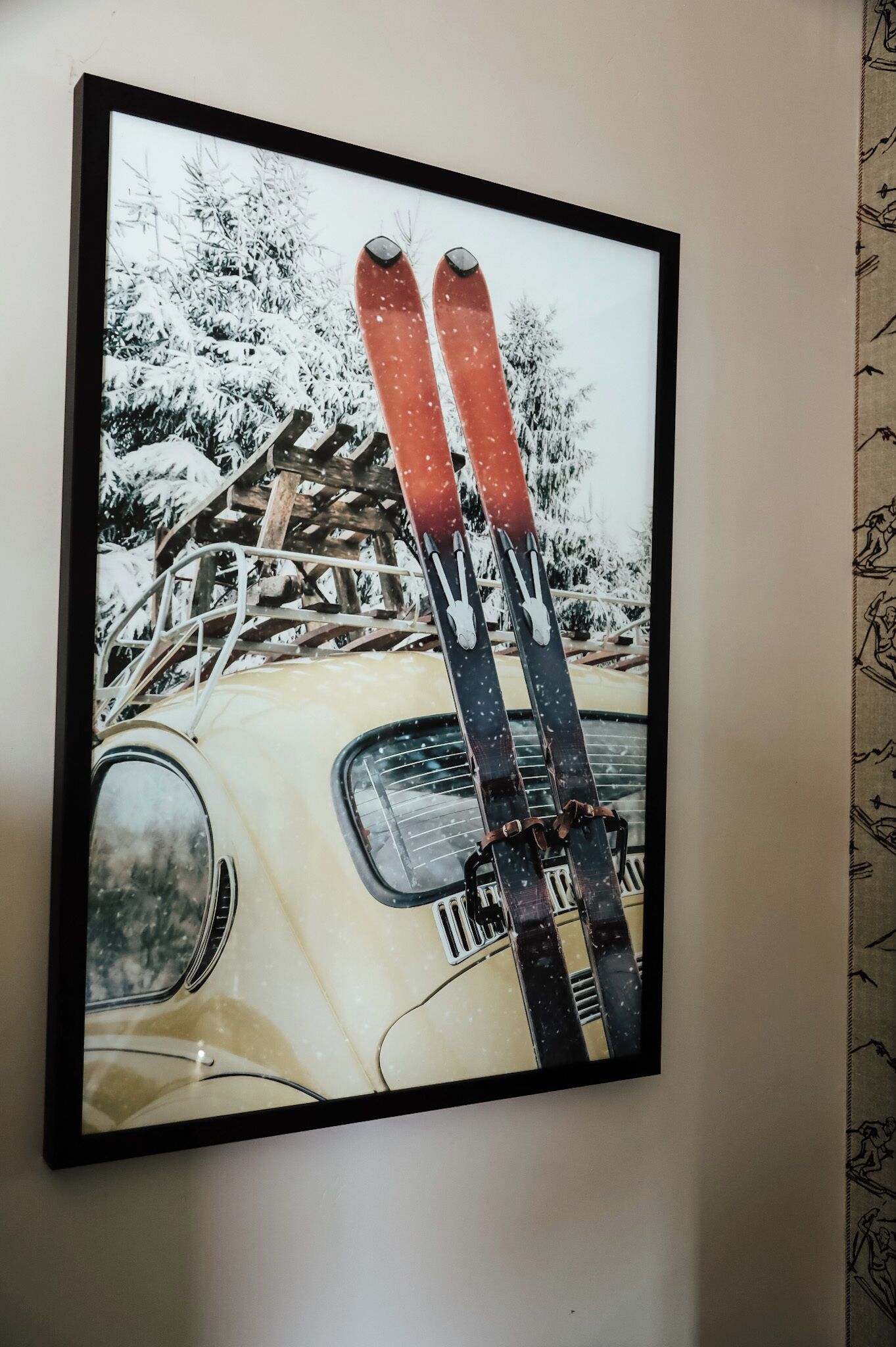 A framed picture of a vintage car with skis on the roof, set against a snowy landscape.