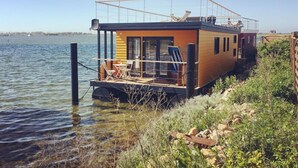 A houseboat with a deck, seating area, and a covered section. - Oostzee Swantje (Heiligenhafen)