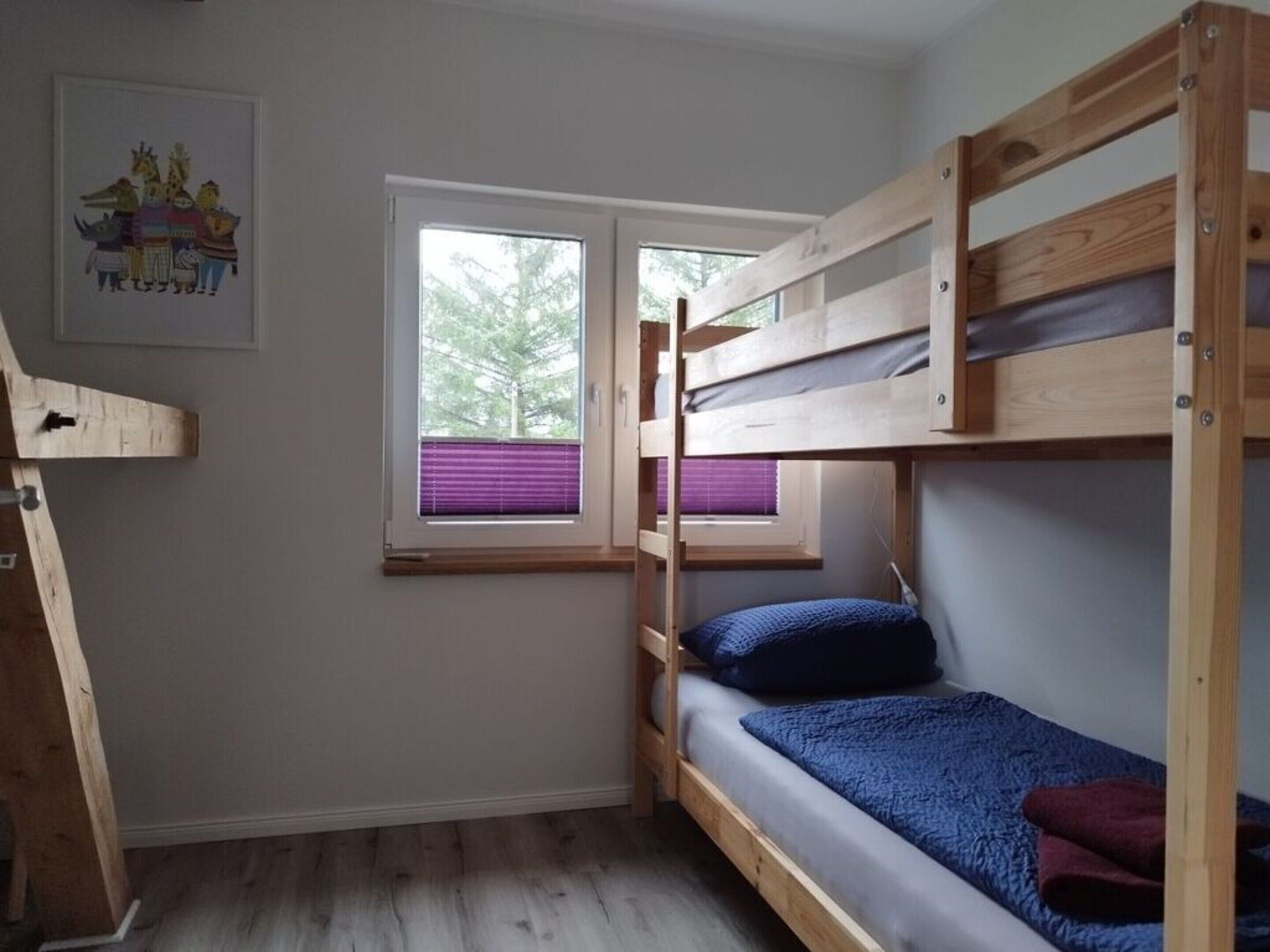 Ett litet sovrum med ett rum, en våningssäng, ett fönster med persienner och en inramad tavla på väggen.