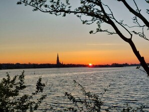 A sunset view over a body of water with a distant building silhouetted against the sky.