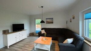 A living room with a TV, a sofa, a coffee table, and a window. - Little Freedom Modern Retreat (Juebek)