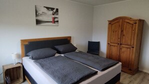 A bedroom with a bed, a wooden wardrobe, a small bedside table, and a wall-mounted picture. - Little Freedom Modern Retreat (Juebek)