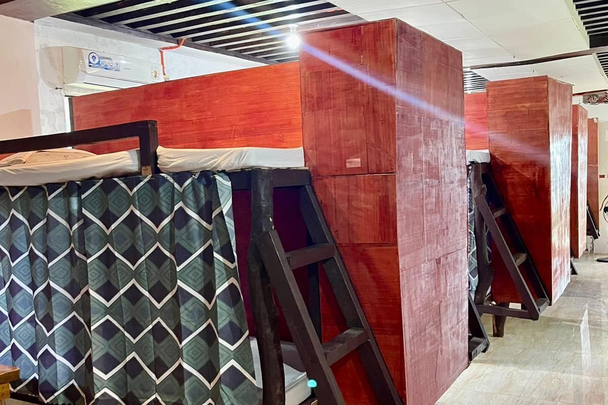 A row of wooden partitions with metal frames, a patterned curtain, and a tiled floor.