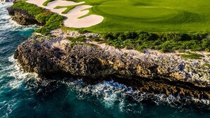 A coastal golf course with bunkers, a clubhouse, and a view of the ocean. - HDM 333 - Golf View Apartment in Exclusive Resort Access to Private Beaches (Punta Cana)