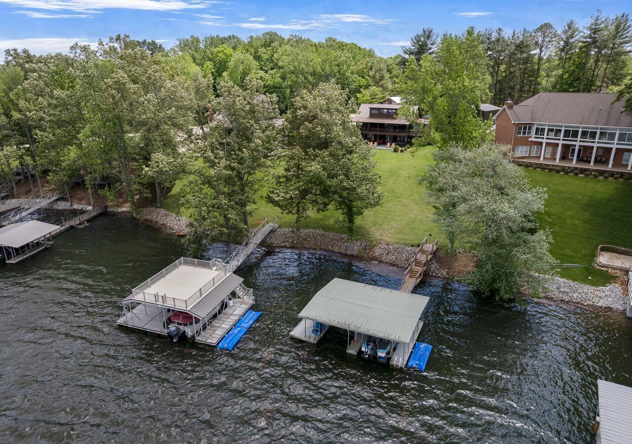 A riverside property with docked boats, a grassy area, and a building with large windows.