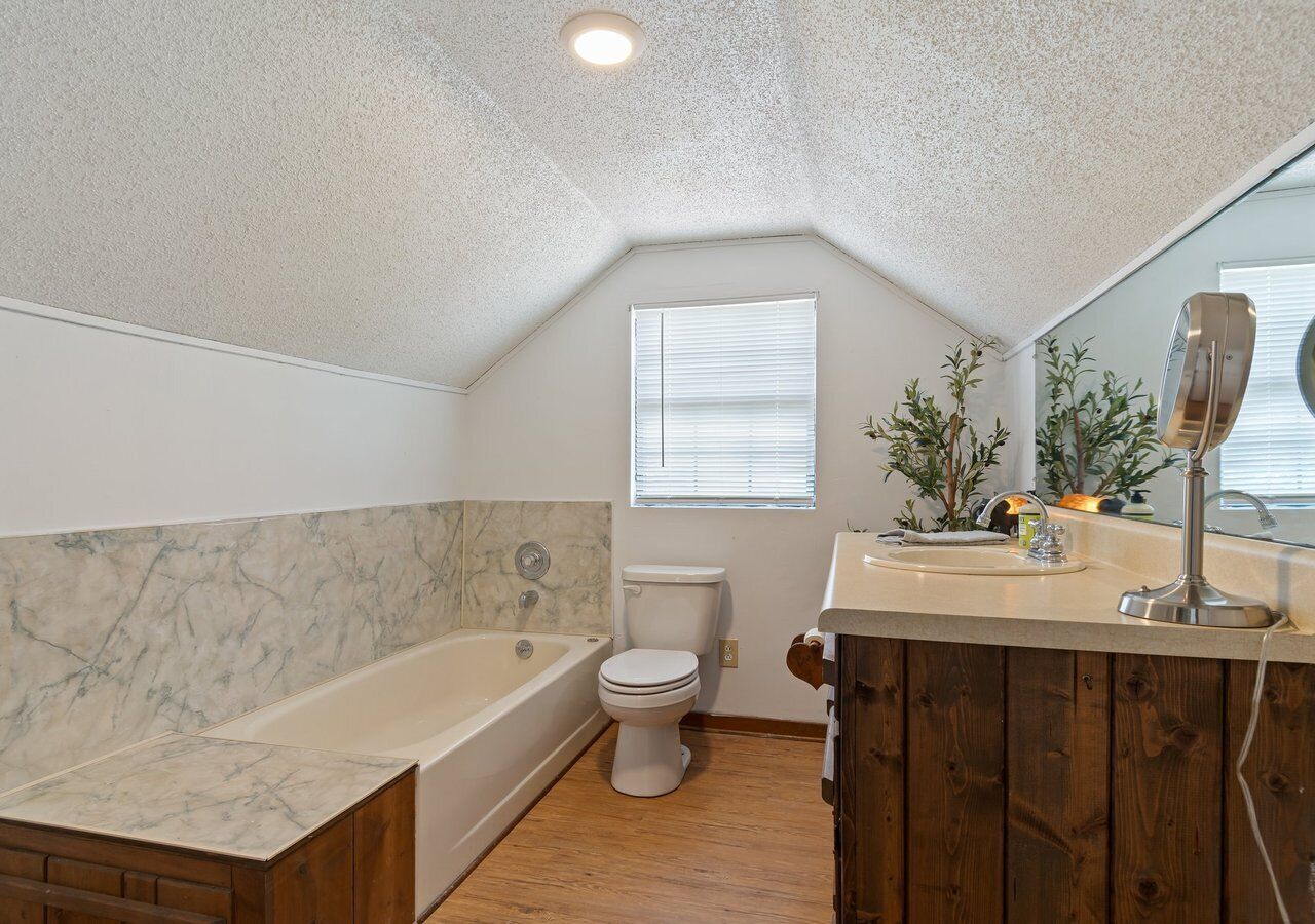A bathroom with a bathtub, toilet, vanity, and a window.