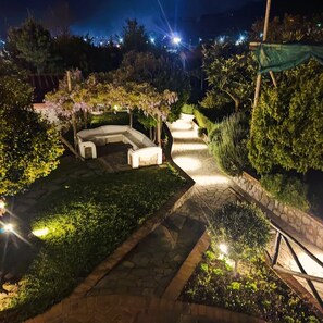 Een goed verlichte tuin met een gebogen zitgedeelte en stenen paden.