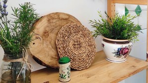 A wooden table with a woven basket, a glass jar with a plant, a ceramic pot with a plant, and a metal wall hanging with a green plate and dried plants. - Comfy Apartment with lush Garden in the heart of  Sant Agata sui due Golfi (Massa Lubrense)