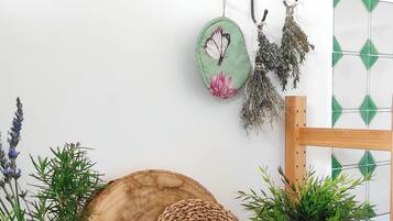 Ein Holztisch mit einem gewebten Korb, einem Glasbehälter mit einer Pflanze, einem Keramiktopf mit einer Pflanze und einem Metallwandbehang mit einem grünen Teller und getrockneten Pflanzen.