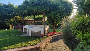 A garden with a white outdoor seating area, a brick pathway, and lush greenery. - Comfy Apartment with lush Garden in the heart of  Sant Agata sui due Golfi (Massa Lubrense)