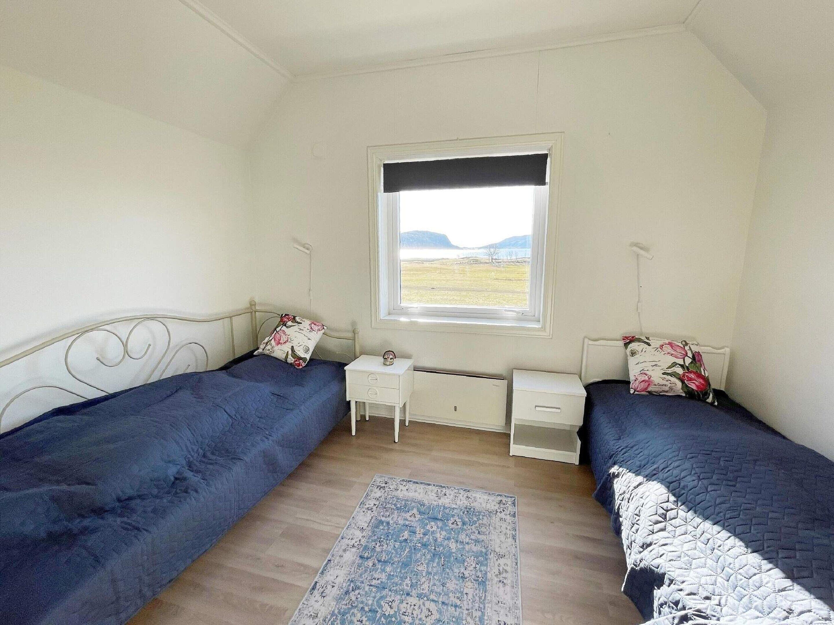 Un dormitorio con dos camas, una ventana, una mesita de noche y una alfombra.