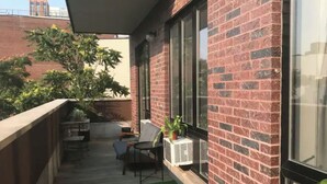 A balcony with a wooden floor, a small table, two chairs, and a potted plant. - Private Deck Paradise  (Brooklyn)