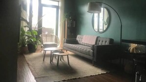 A living room with a sofa, a coffee table, a floor lamp, and a large mirror on the wall. - Private Deck Paradise  (Brooklyn)