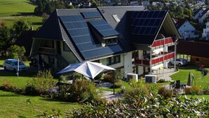 A house with solar panels on the roof, a covered patio, and a view of a green landscape. - Holiday Apartment Kieschtock (Unterkirnach)