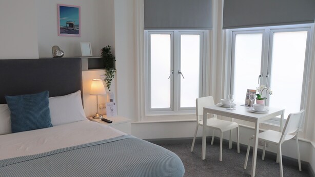 Ein Schlafzimmer mit Bett, Nachttisch, Lampe und einem Fenster mit Blick.