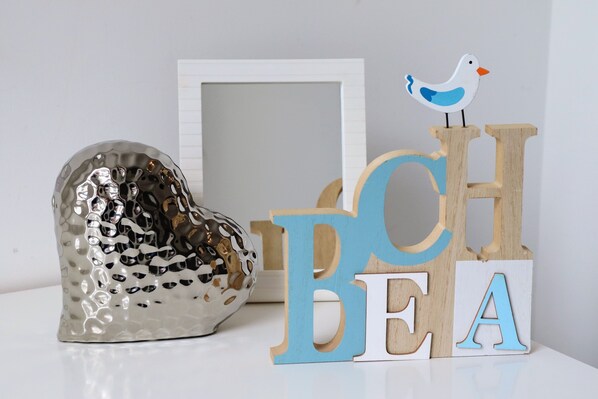 A decorative arrangement with a heart-shaped object, wooden letters spelling "BEACH," and a bird figurine.