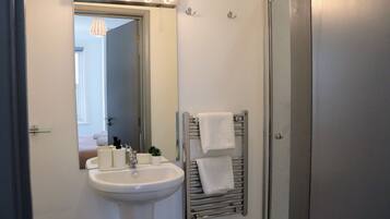 A bathroom with a sink, mirror, towel rack, and a door.