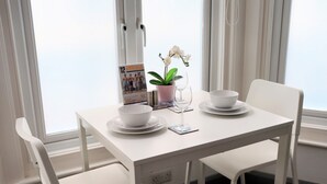 Ein weißer Tisch mit einem Topf-Orchideenstrauß, einem Glas und einer Schale.