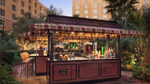 An outdoor bar with a striped awning, bar stools, and a variety of bottles. - Wyndham Grand Desert 2 BR Deluxe - Full Resort Access -25% Deposit to Book NOW! (Las Vegas)