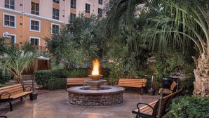A courtyard with a stone fire pit, benches, and lush greenery. - Wyndham Grand Desert 2 BR Deluxe - Full Resort Access -25% Deposit to Book NOW! (Las Vegas)