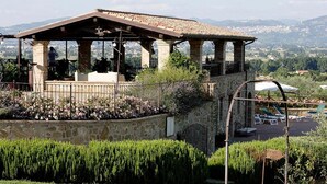 A stone structure with a tiled roof, possibly a terrace or viewing platform, surrounded by a stone wall and lush greenery. - Casa Vacanze a Bettona con Giardino (Bettona)