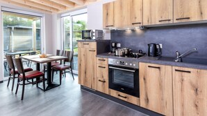 A modern kitchen with wooden cabinets, a built-in oven, and a dining area with a table and chairs.