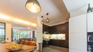 Une cuisine moderne avec des meubles de couleur sombre, un réfrigérateur blanc et un coin repas comprenant une table et des chaises en bois.