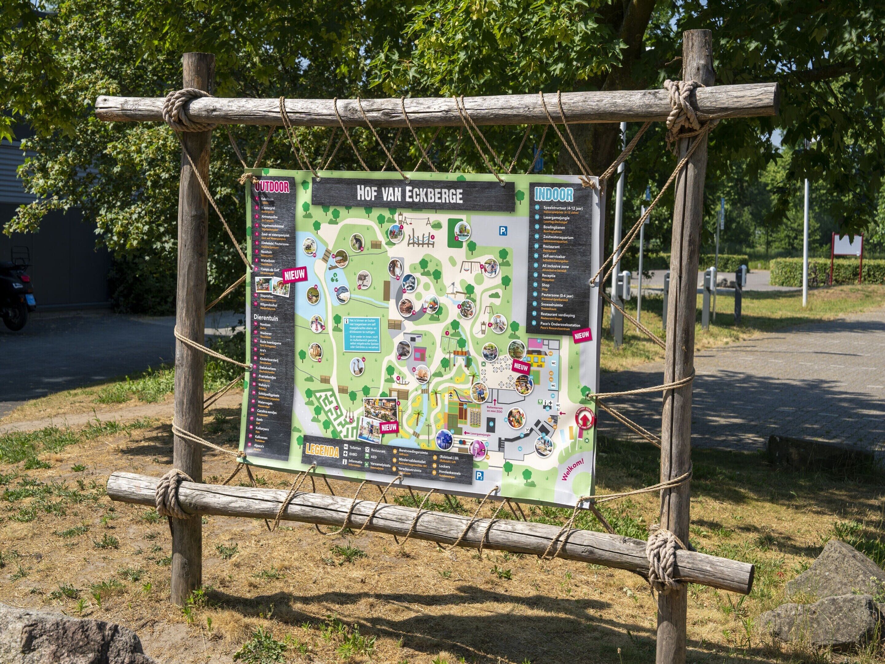 A wooden signpost with a map and lists of amenities for Hof Van Eckberge.