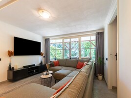 Una sala de estar moderna con un ventanal grande, un televisor de pantalla plana y un conjunto de sofás.