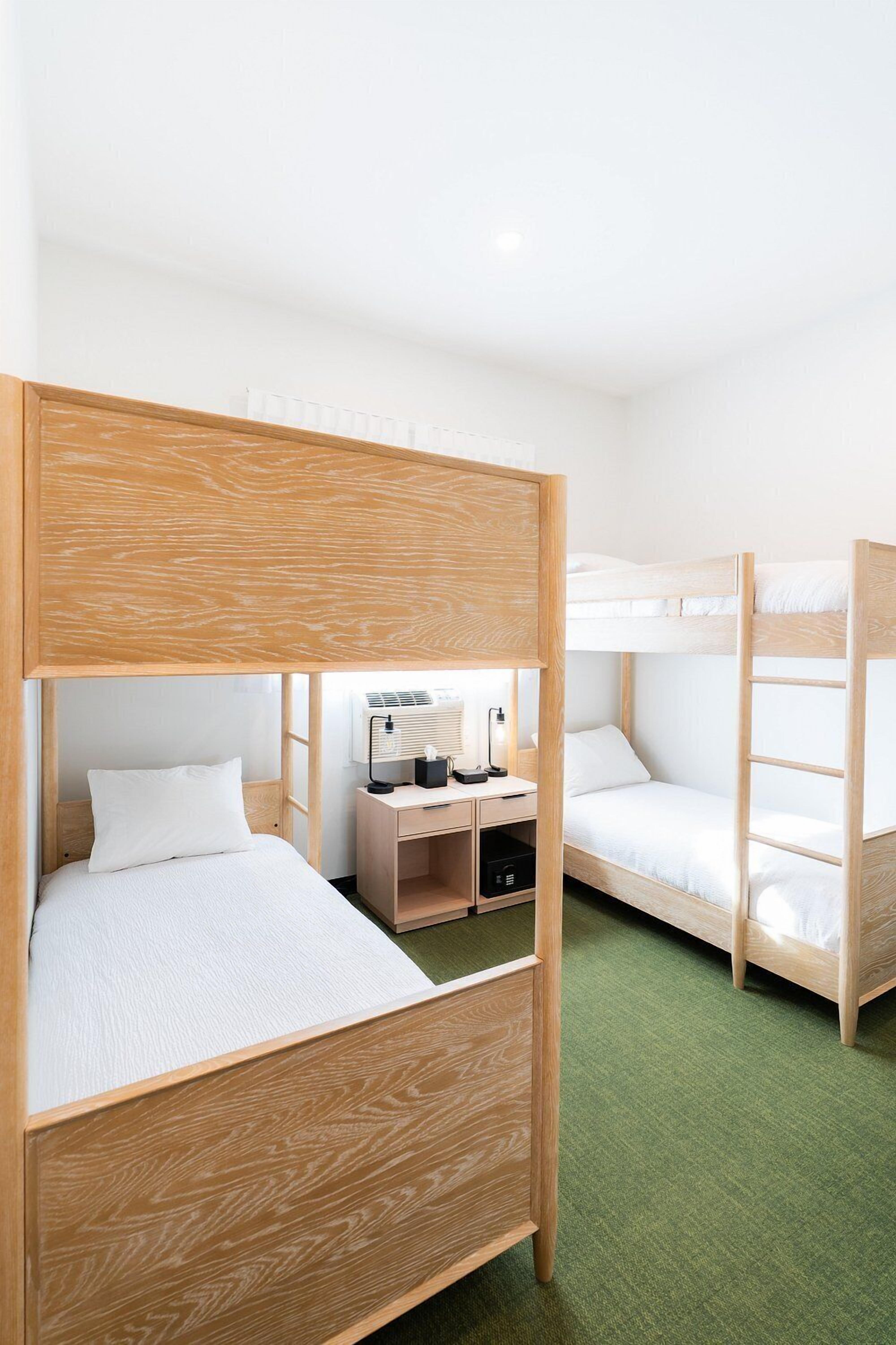 Una habitació amb lliteres, un escriptori amb una làmpada i una petita estant.