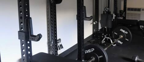 A gym with a squat rack, bench, and weight plates.