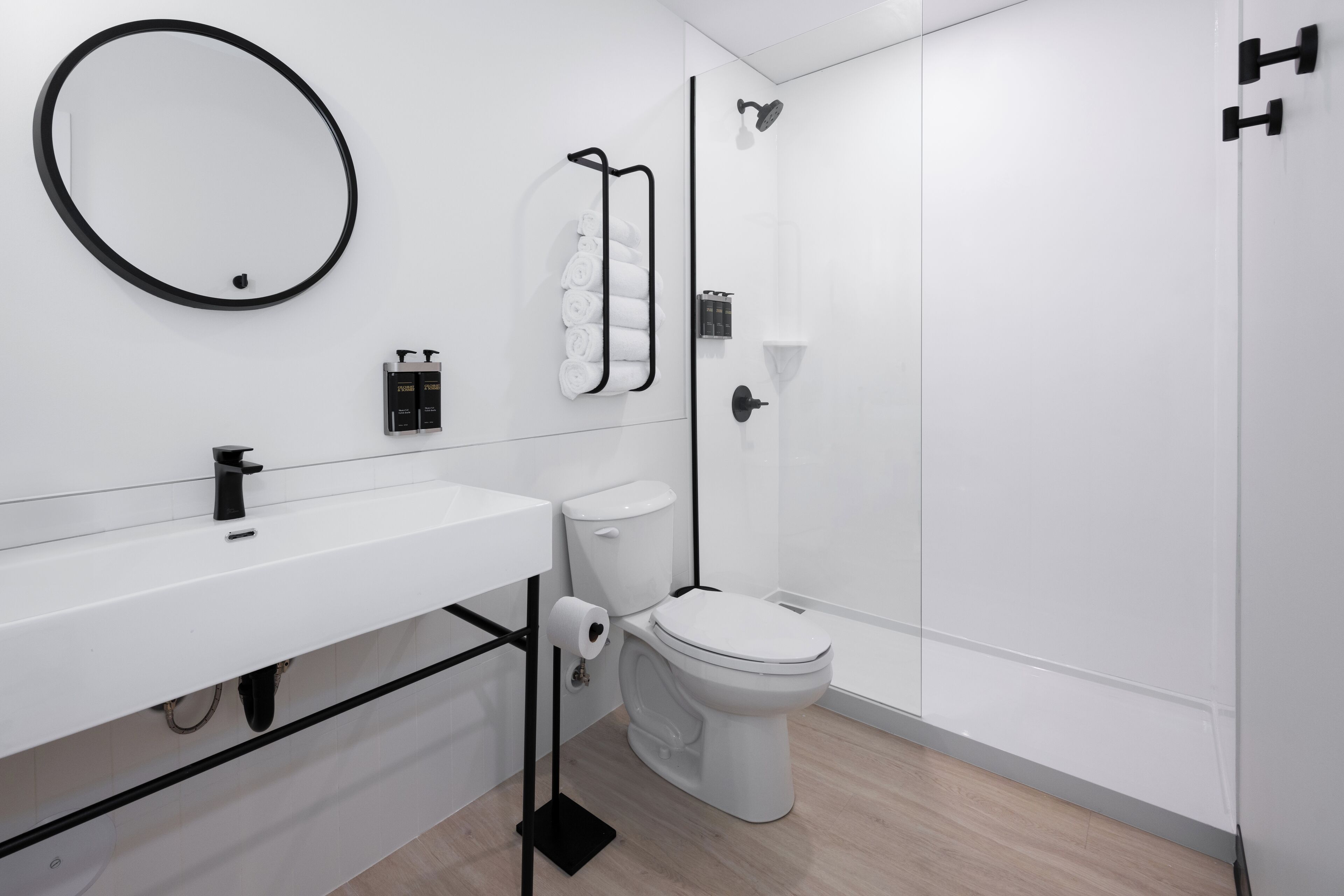 Een moderne badkamer met een wit wastafel, toilet en douche.