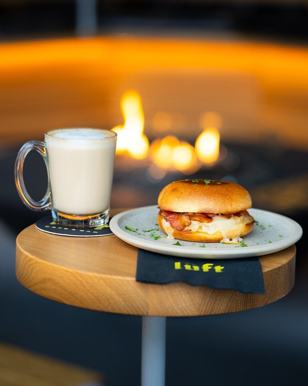A wooden table with a plate of food and a glass of beverage.