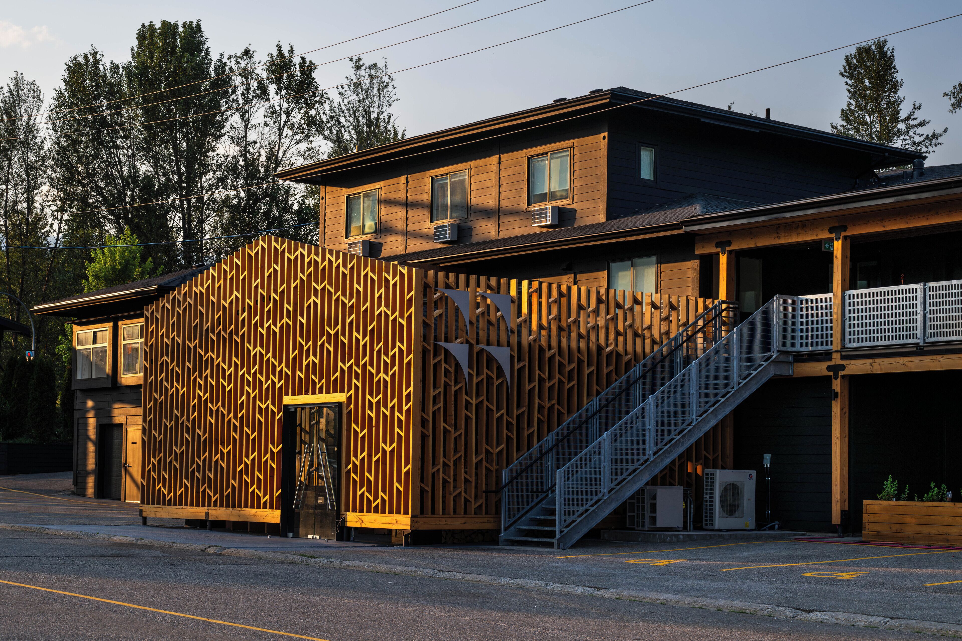 Un bâtiment moderne doté d’une façade en bois, d’un escalier menant à un deuxième étage et d’une entrée abritée.