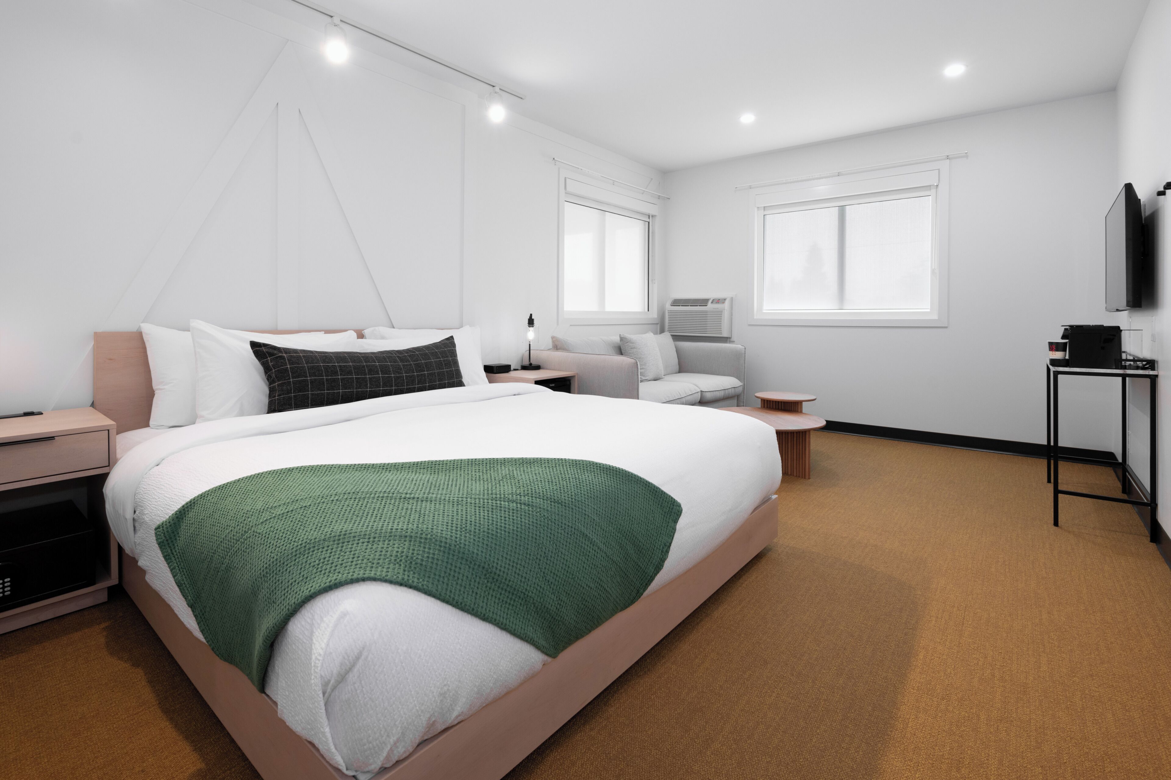 Une chambre d’hôtel moderne, dotée d’un grand lit, de tables de chevet, d’un bureau, d’une chaise, d’une télévision et d’une fenêtre.