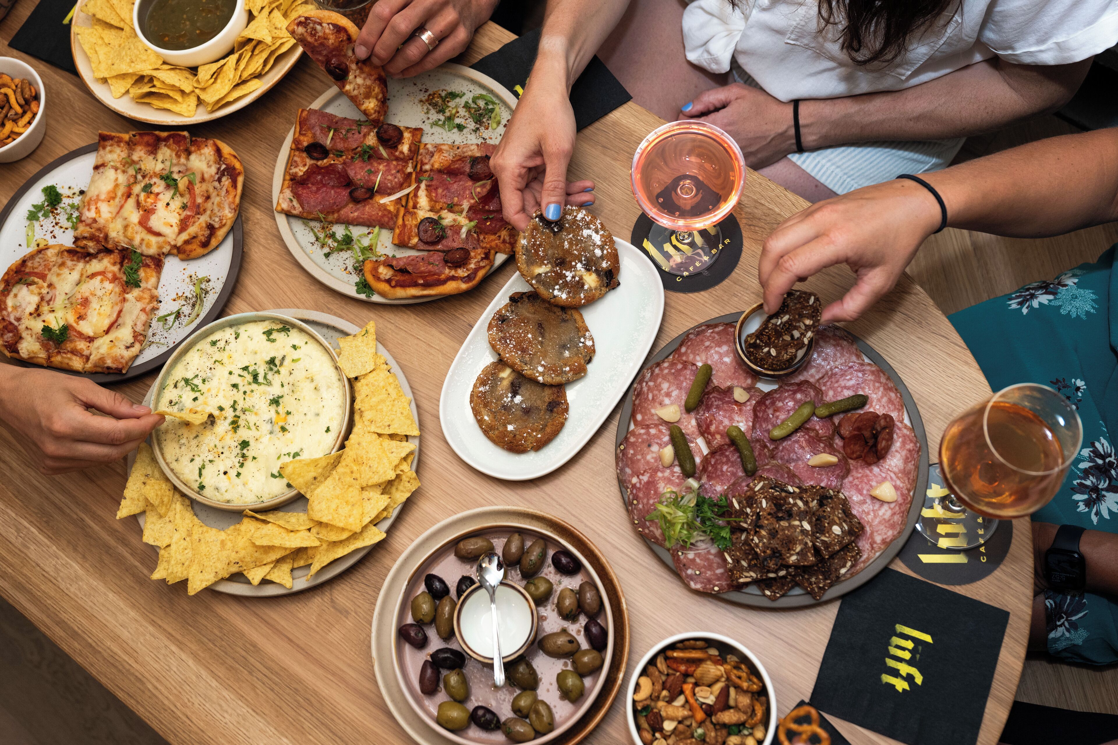 Una mesa con diferentes comidas, como pizza, nachos y una salsa de queso.