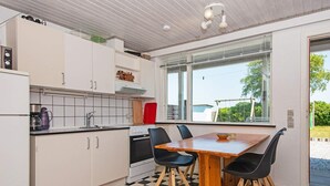 Cocina compacta con piso a cuadros, una mesa de comedor con cuatro sillas y ventana con vista a un jardín.