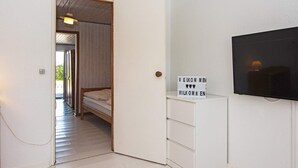 Un dormitorio con una cama, una mesita de noche, un televisor y un cartel con la palabra 'Welcome' en inglés y alemán.