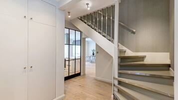 A modern interior with a staircase, wooden flooring, and a view into another room.
