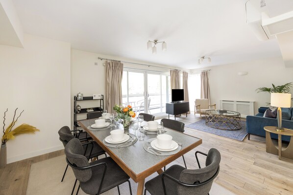 Una habitación de hotel moderna con comedor, sala de estar y televisor.
