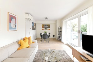 Una sala de estar moderna con sofá, televisión y zona de comedor.