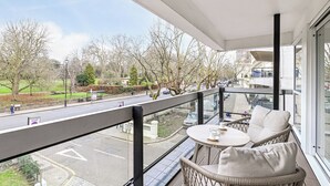 A balcony with wicker furniture and a view of a city street and park. - Stylish Kensington Apartment with Hyde Park View Terrace · Sleeps 4 (London)