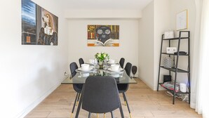 A dining area with a glass table, black chairs, and a bookshelf. - Stylish Kensington Apartment with Hyde Park View Terrace · Sleeps 4 (London)