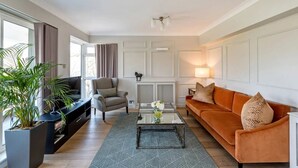 Un salón con sofá, sillón, mesa de centro y una planta en maceta.