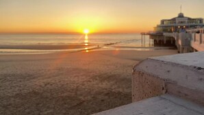 Une scène de plage avec une jetée qui s’avance dans l’eau au coucher du soleil.