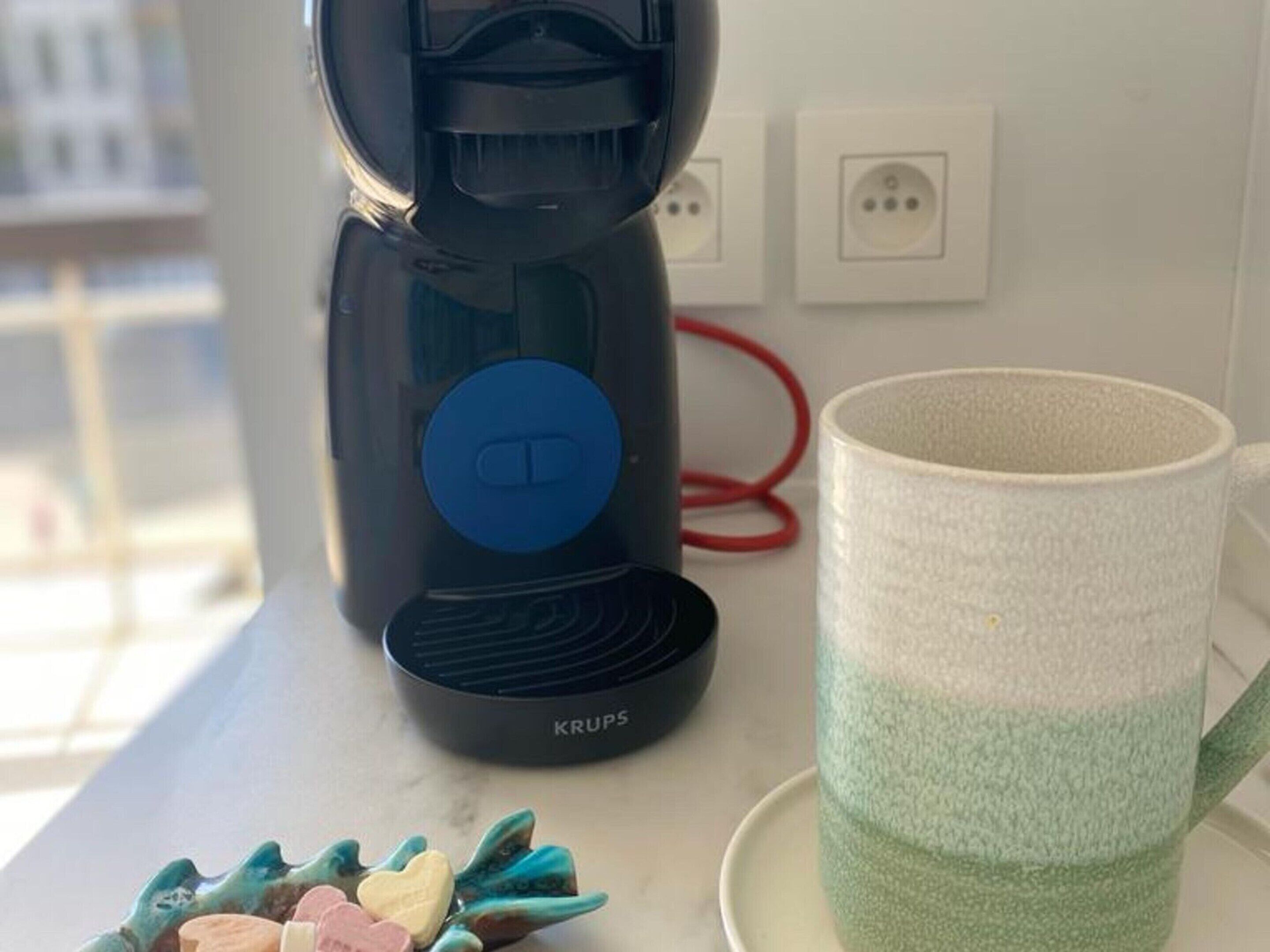 A coffee maker with a blue control panel and the brand name 'KRUPS' on a kitchen counter.