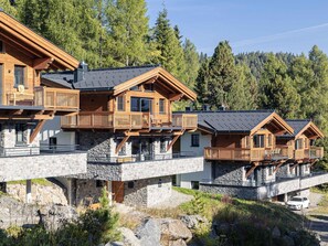 A modern chalet with multiple wooden balconies, stone foundations, and a mountainous backdrop. - Superior Chalet With Sauna (Stadl-Predlitz)