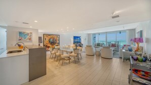 En moderne opholdsstue med spiseplads, køkken og siddeområde med havudsigt.